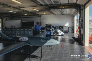 Drone à hydrogène "RAPACE" et une voiture de course d'endurance automobile à propulsion électrique-hydrogène de la mission H24, dans un garage du circuit automobile Paul Ricard (Le Castellet - Var).